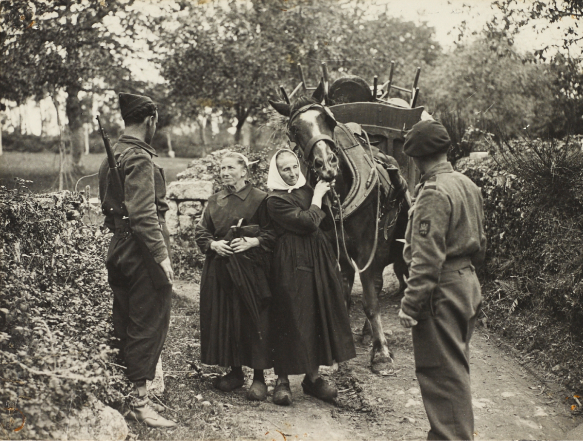 Le front d'Etel en septembre 1944. Deux combattants des F.F.I. font face à deux vieilles femmes en costume et coiffe du pays de Lorient. Leur cheval de trait est chargé de chaises et d'autres objets emportés dans la fuite de la poche de Lorient, bombardée.